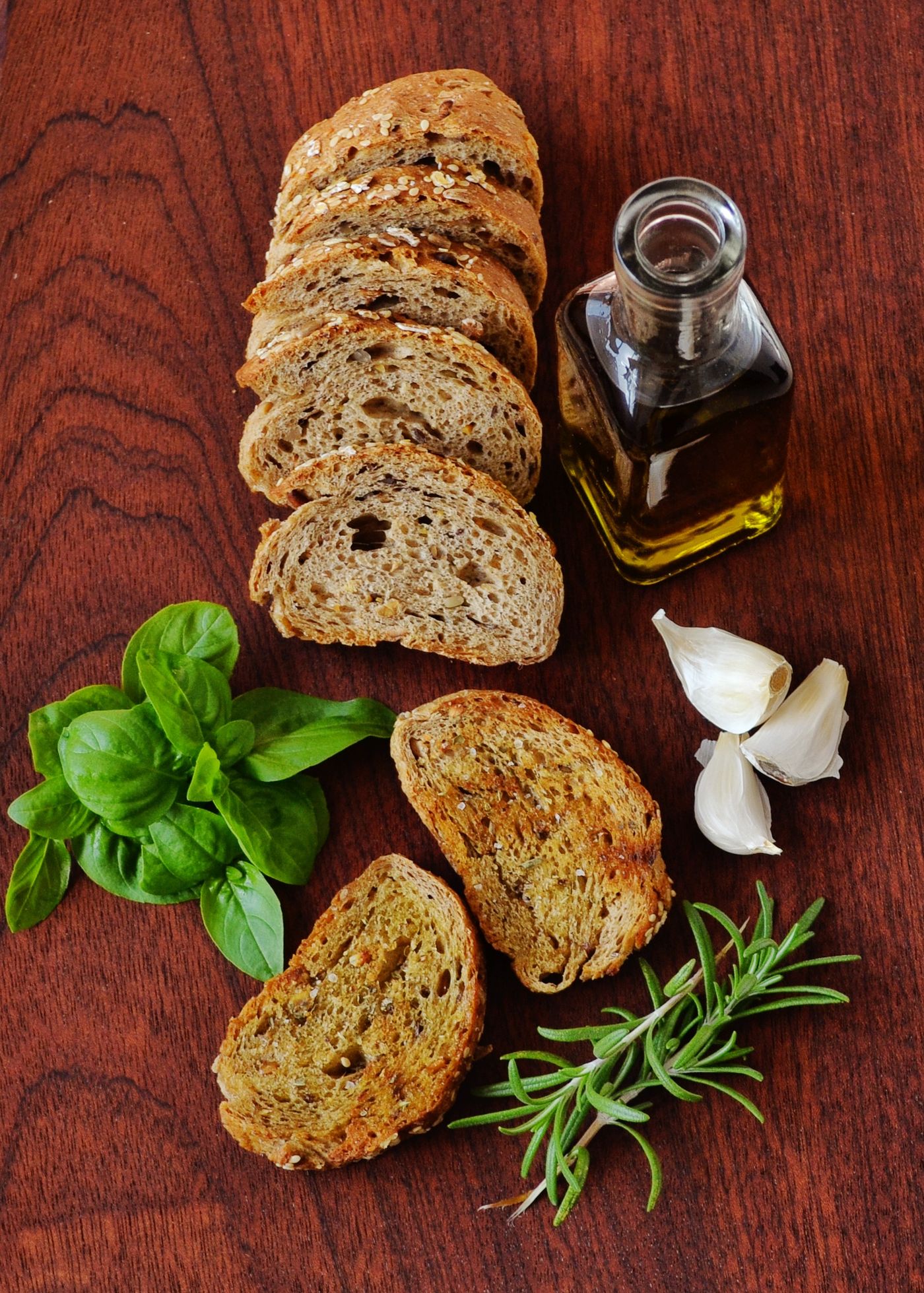 Pan rústico, aceite de oliva y hierbas sobre una mesa de madera